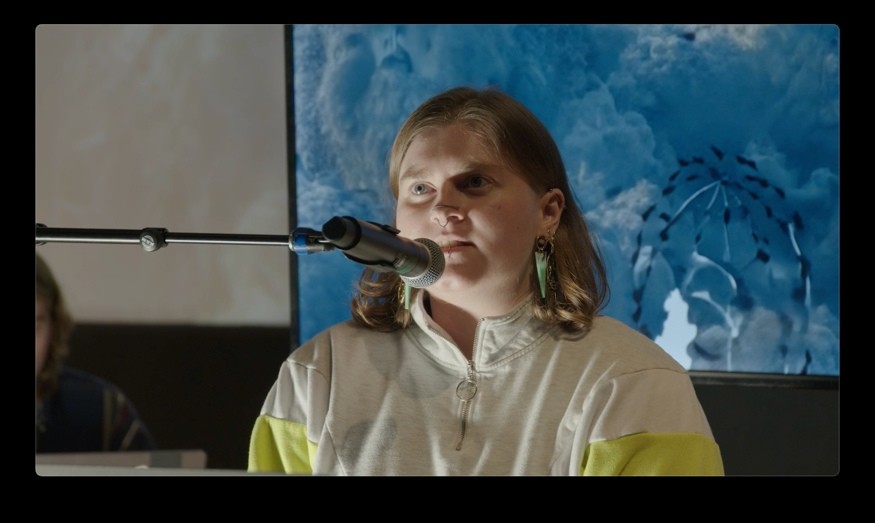 A reader speaks into a microphone in front of a projected flock.